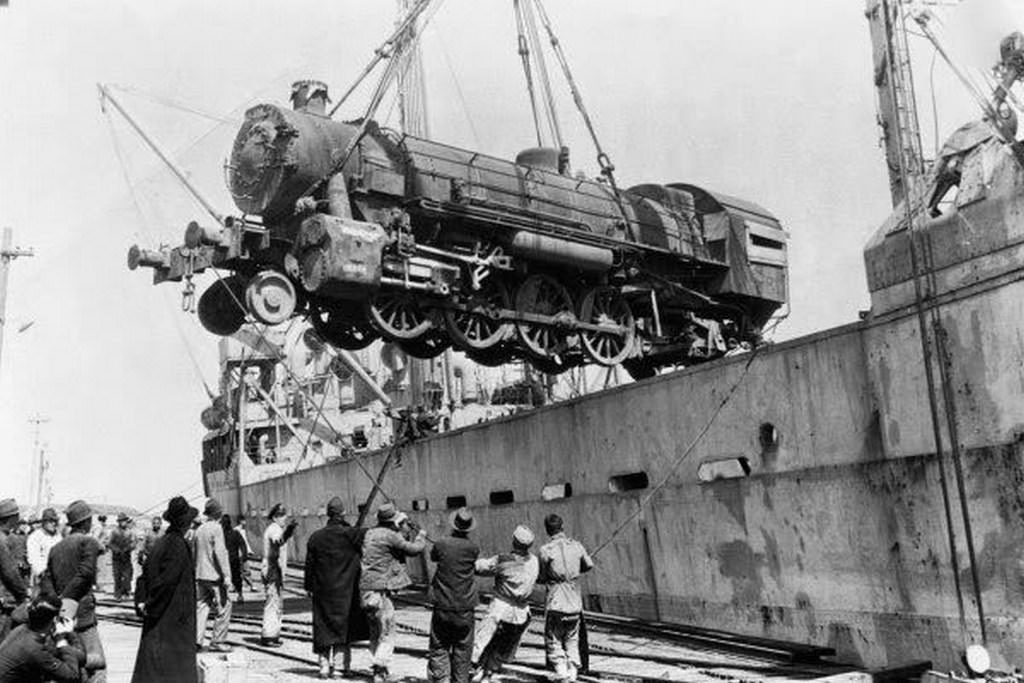 Dockers unloading a train locomotive engine; this engine car was provided by the United Nations Relief and Rehabilitation Administration