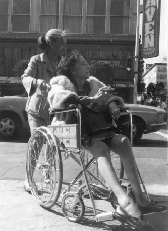 Old woman in wheelchair with cigarette, Polk Street, San Francisco, 1975