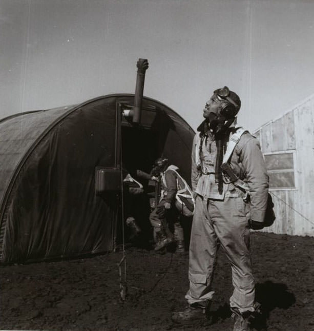 Pilot Newman C. scanning the skies, with parachute room in background