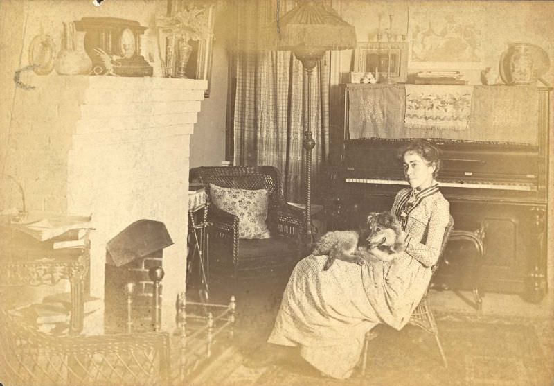 Woman seated by fireplace with dog in lap