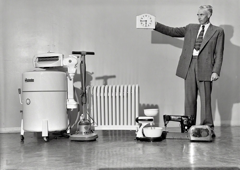 A man with hgousehold appliances including washing & sewing machine, mixer, toaster, polisher and heater, Wellington, New Zealand, circa 1950