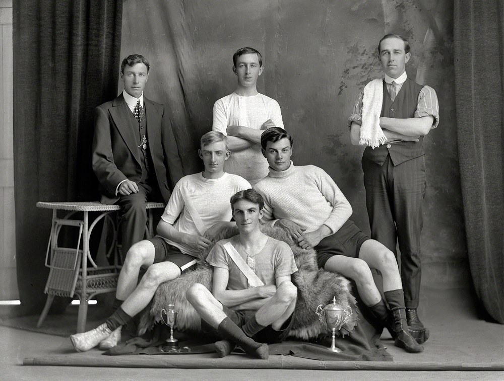 Bicycle road racing team with four young men in riding attire with two small cups, Christchurch, New Zealand circa 1910