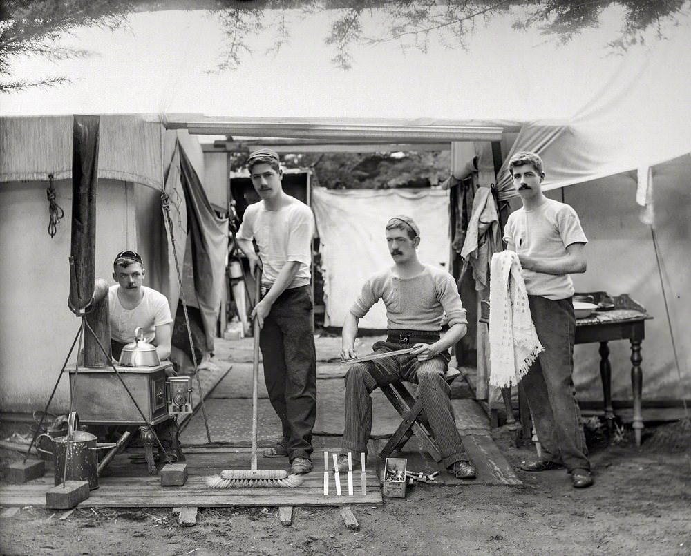 Young men doing chores, next to tent at a camp site, probably Christchurch district, New Zealand circa 1905