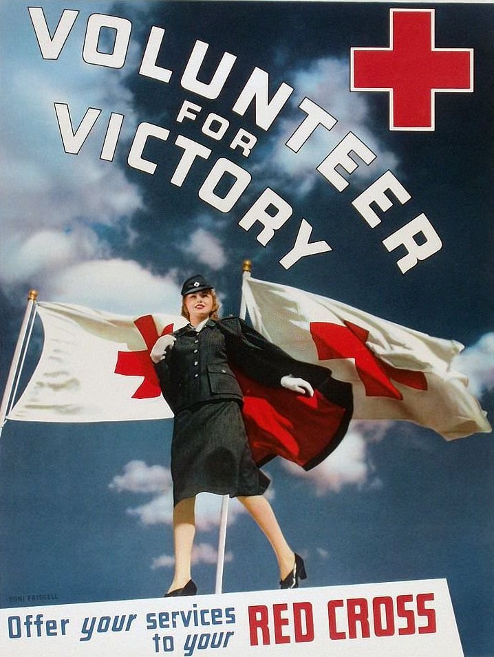 A female Red Cross volunteer standing in front of two Red Cross flags.