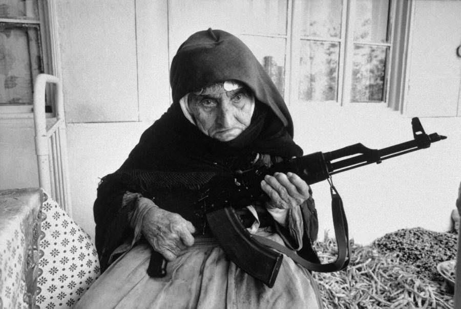 A 106-year-old woman sits in front of her home guarding it with a rifle, in Degh village, near the city of Goris in southern Armenia in 1990.