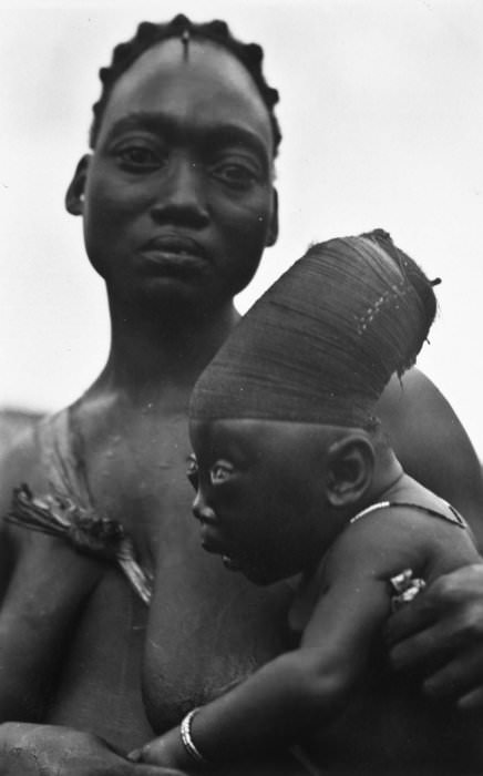 A woman of the Democratic Republic of the Congo's Mangbetu tribe holds her child, circa 1929-1937.