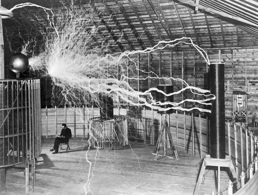 Serbian scientist Nikola Tesla sits near his magnifying transmitter.