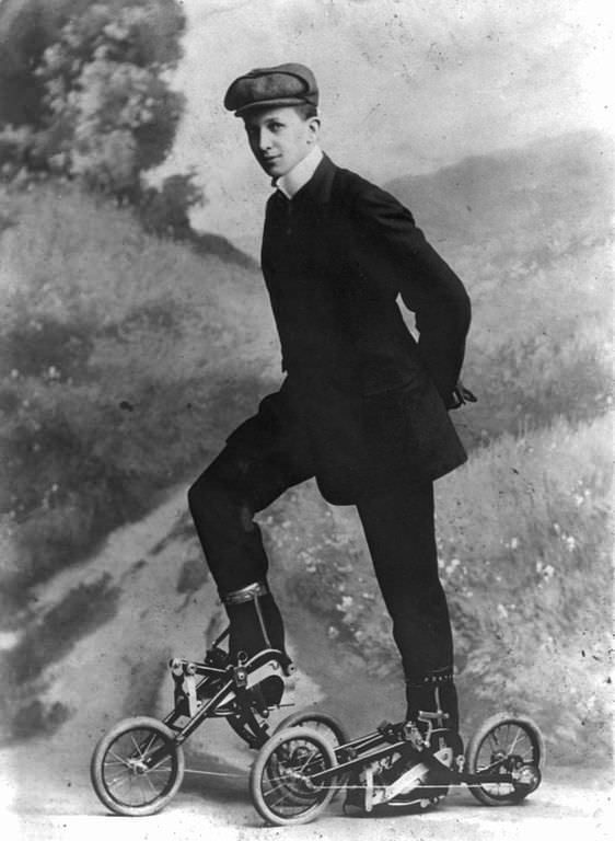 A man wears an early version of roller skates powered with pedals and wheels, 1910.