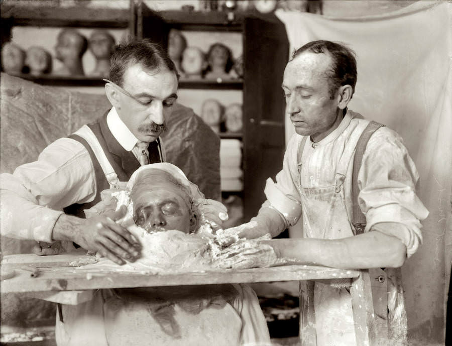 Two men construct a death mask in New York, circa 1908.