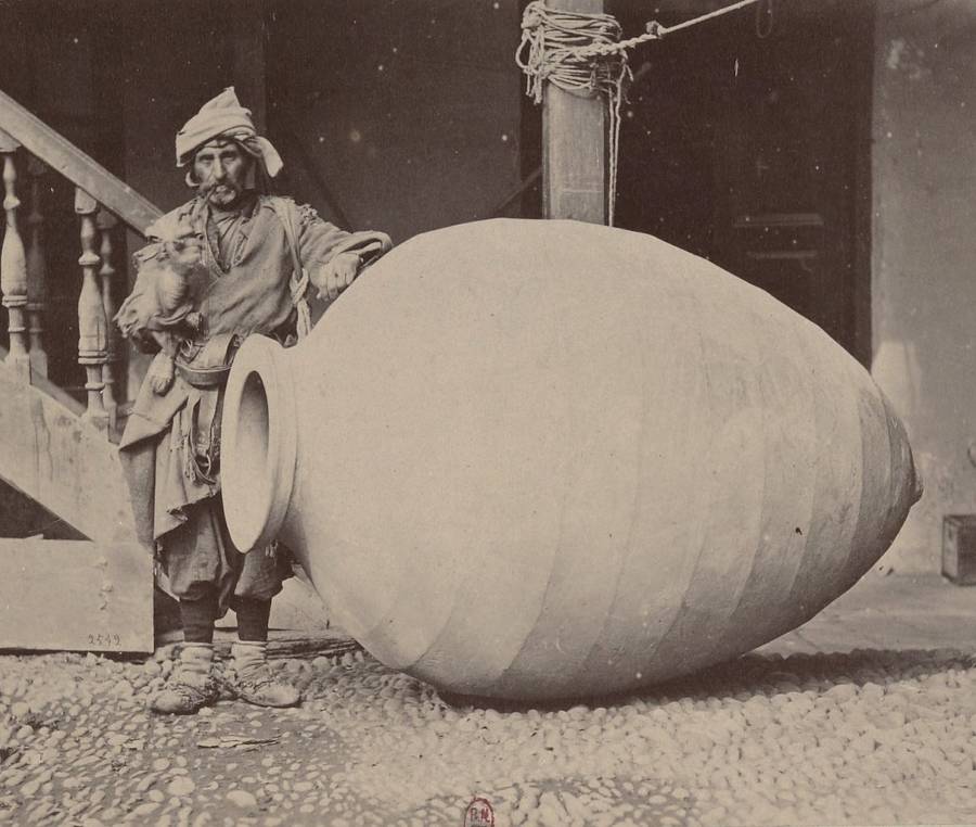 A man stands next to an enormous container used to store wine in Kakheti, Georgia, 1881.