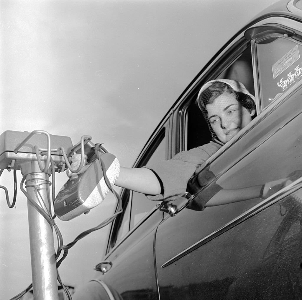 A woman listens to a sermon from her car at a drive-in church service, 1955