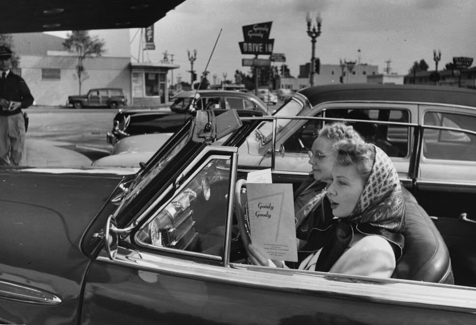 A young motorist studies the menu at a Hollywood drive-in restaurant.