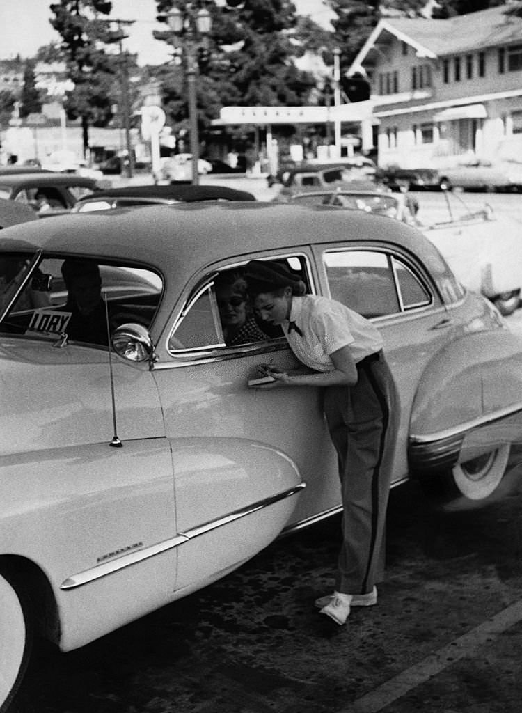 A young waitress notes down a motorist's oder at a drive-in restaurant in Hollywood.