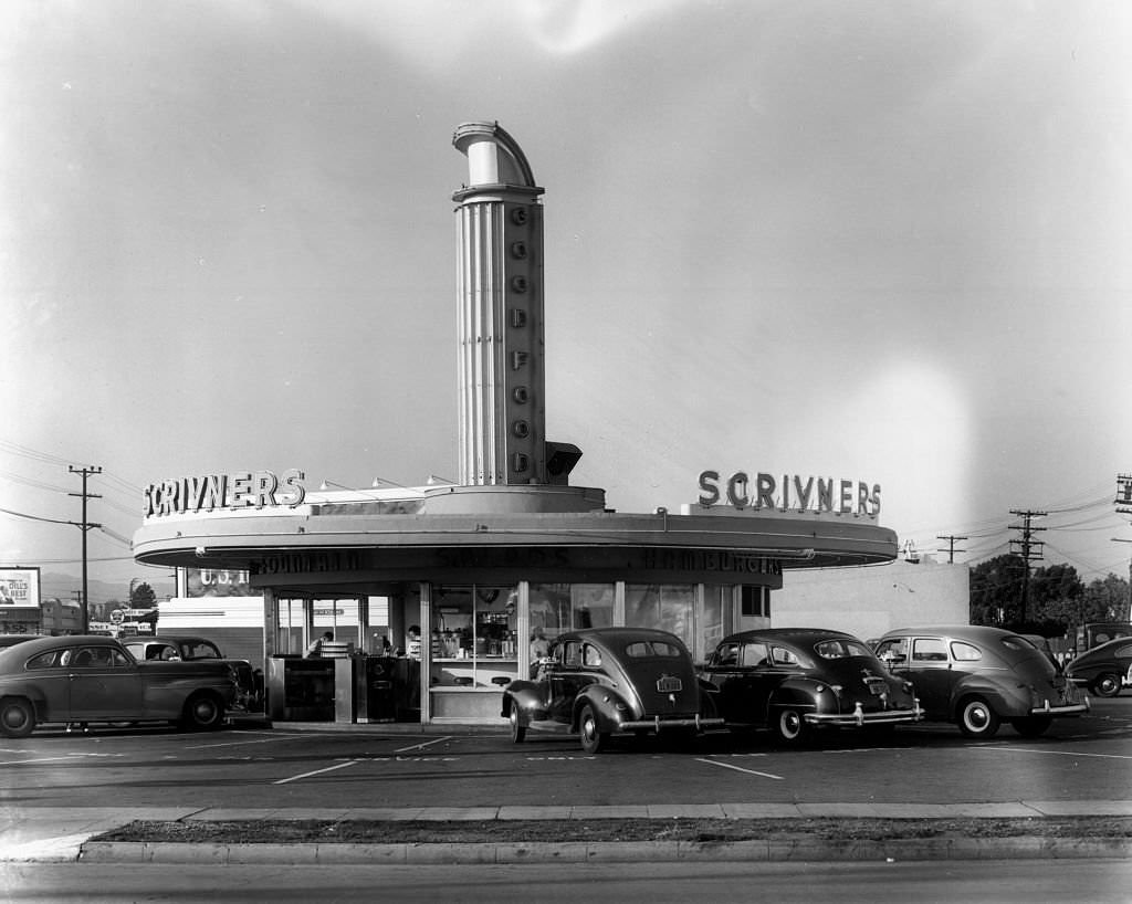 A view of Scrivner's Restaurant which is a circular building cars parked around it.