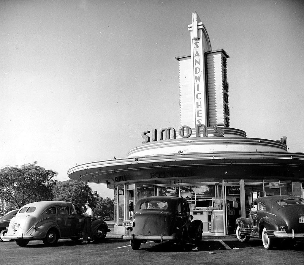 Three cars parked at a Los Angeles drive-in cafe, with a waitress serving at one car