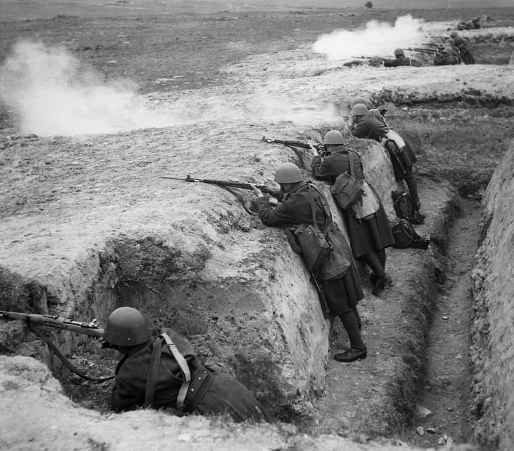 Czechoslovakian troops stand in a trench with rifles, preparing to defend themselves against the Germans.