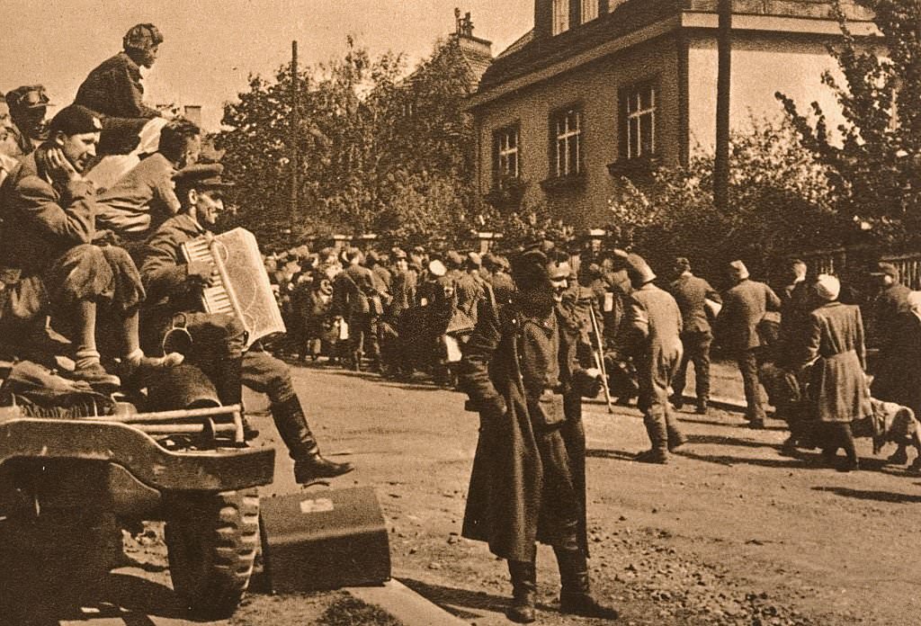 Soldiers play an accordion in celebration of the defeat of Germany as refugees file by at the end of World War II in Czechoslovakia.