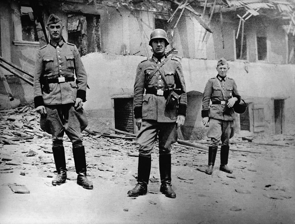 German soldiers pose in front of the burnt out shell of a farmhouse in Lidice.