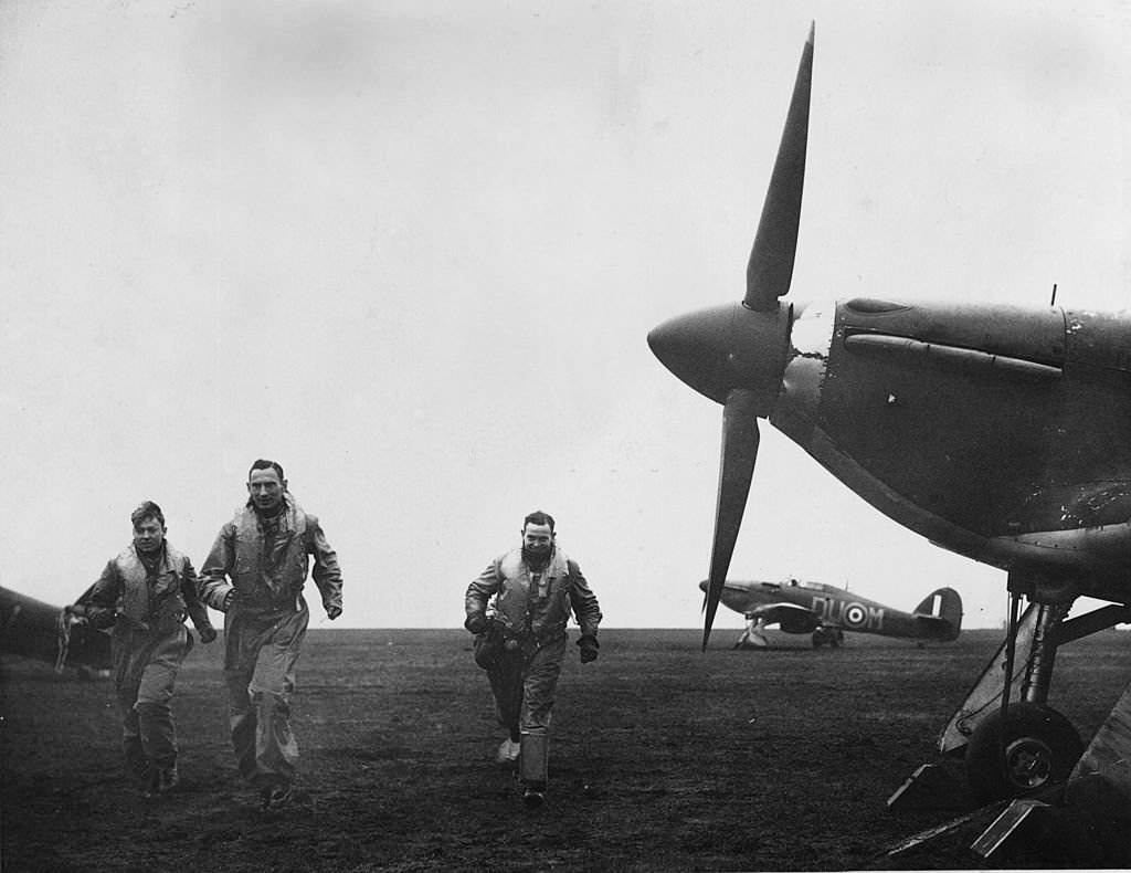 Czechoslovakian pilots running to their Hurricane fighter planes on an airfield 'somewhere' in the north of England after receiving an alert.