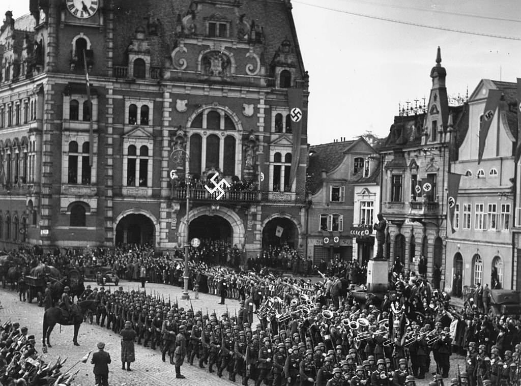 Troops of the German army march into Czechoslovakian territory and parade in the town square at Rumberg, which has been decorated with swastika banners.