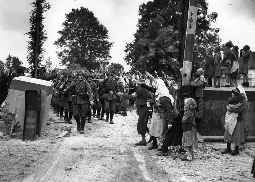 Troops of the German 'defence force' (Wehrmacht) are welcomed as they march across the border at Wald Haenst into Czechoslovakia.