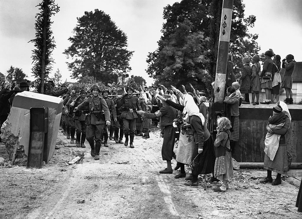 Peasants give German soldiers the Hitler salute as they cross the Czechoslovakian border