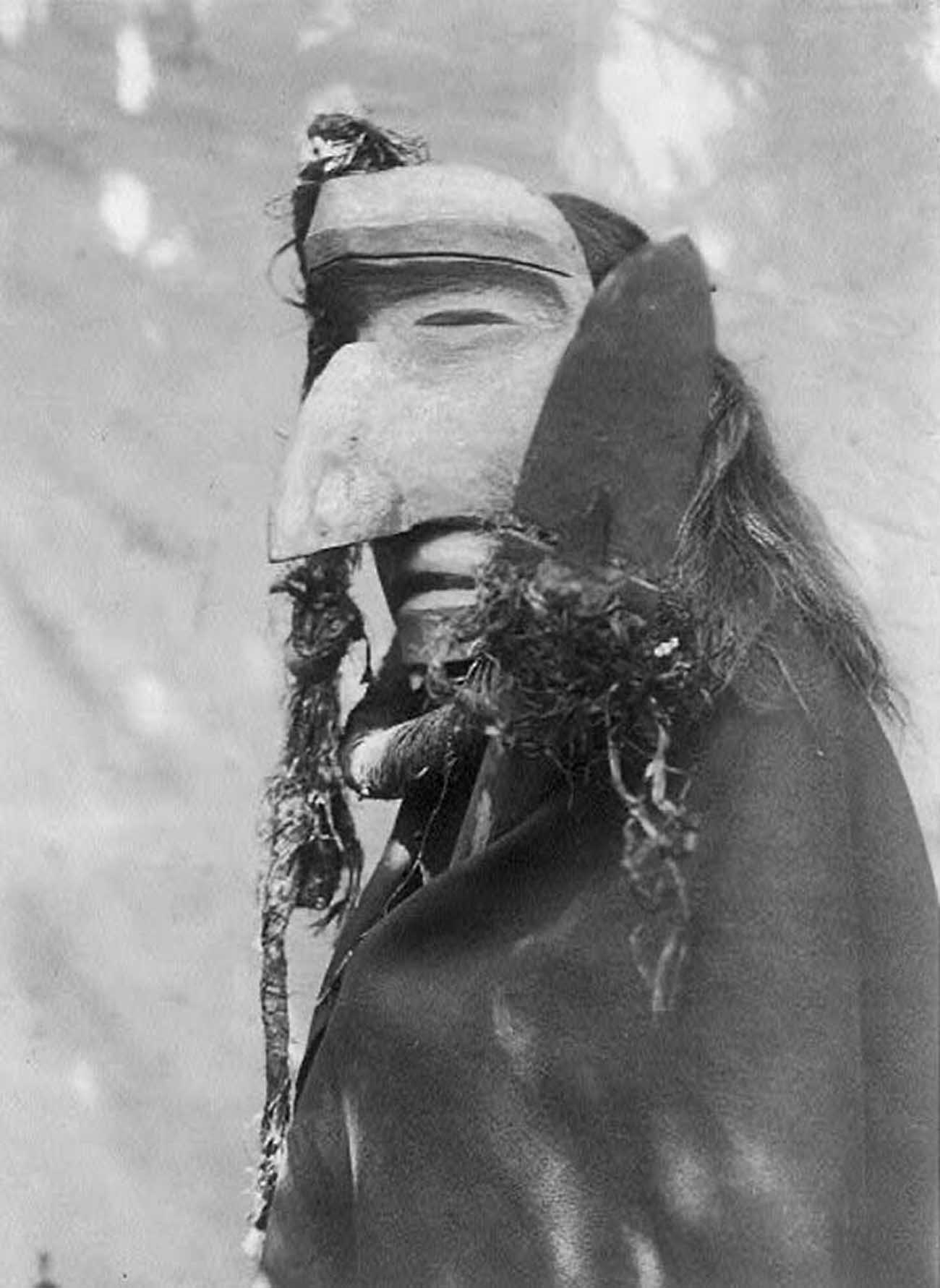 Person wearing ceremonial mask of the Nuhlimahla during the Winter Dance ceremony.