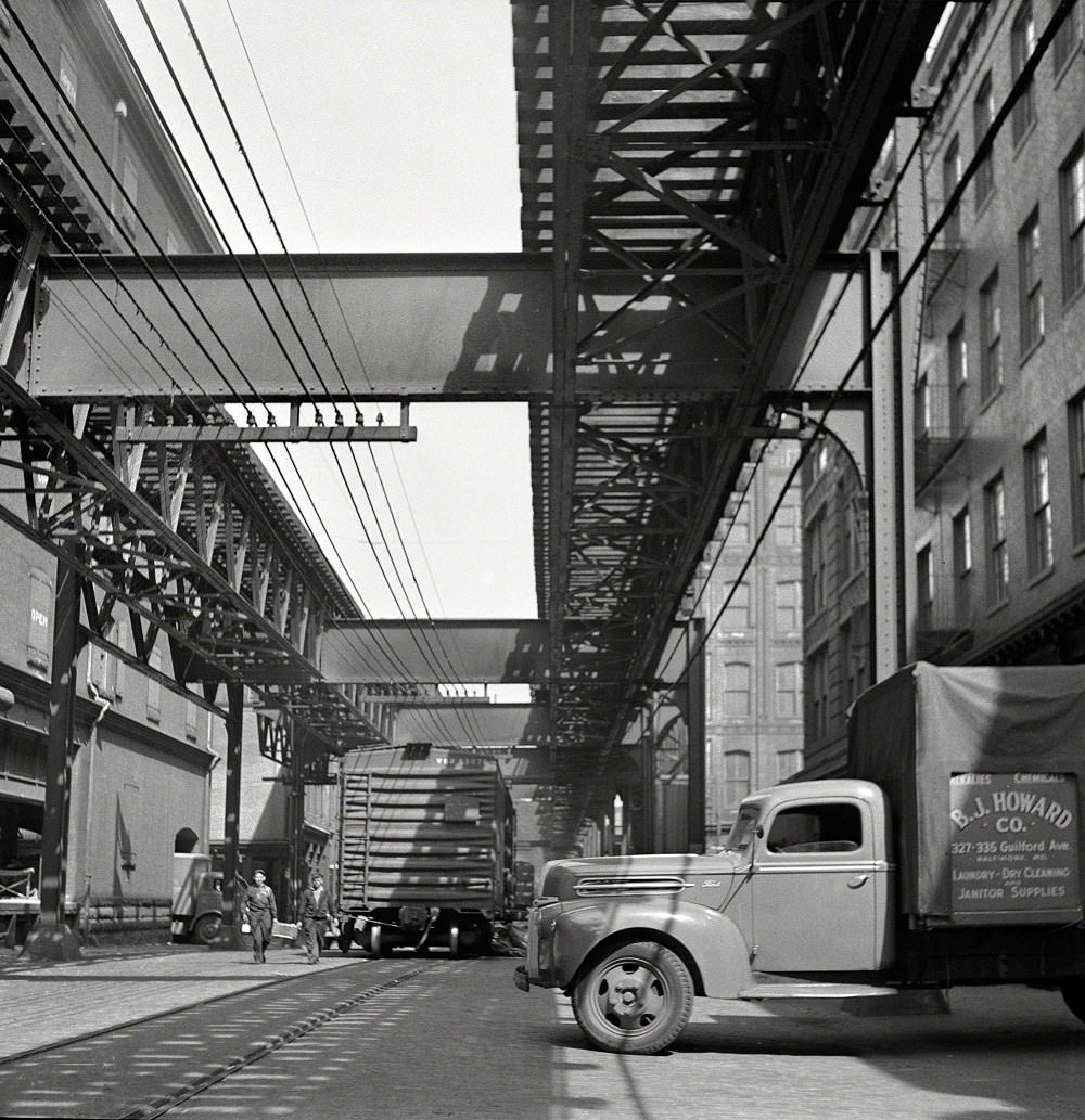 Trucks and trains unloading goods underneath elevated trolley, Baltimore, Maryland, April 1943