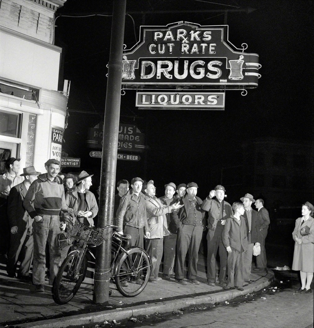 Workers waiting on a street corner to be picked up by car pools around midnight, Baltimore, 1943