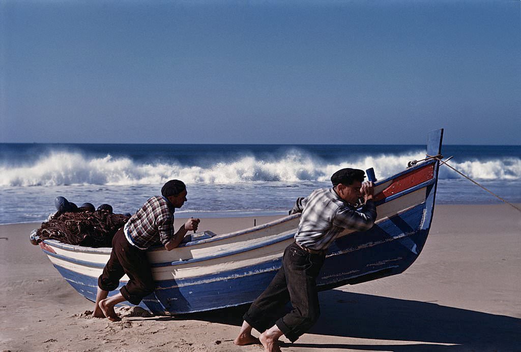 Fishermen pulling their boat up the beach at Nazare, Portugal, 1952.