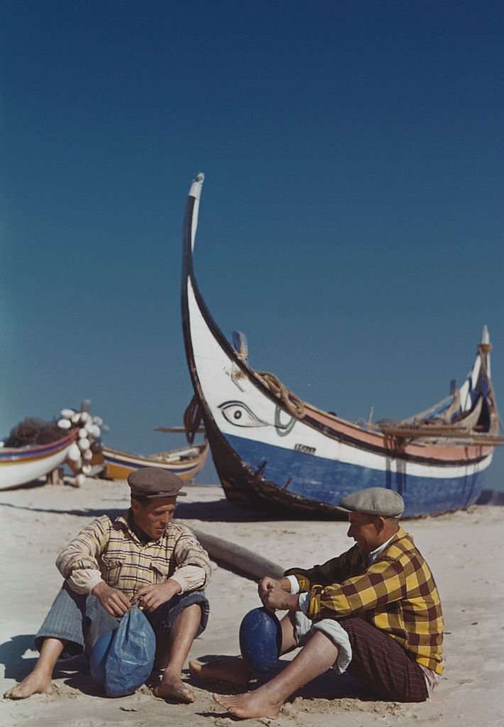 Portuguese fishermen prepare their nets on the beach at Nazare, Portugal, 1955.