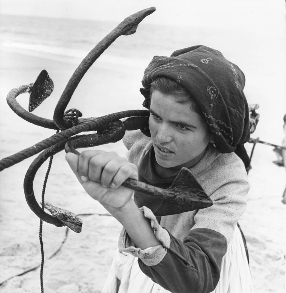 A woman helps to pull in the fishing boats at Peniche, Portugal.