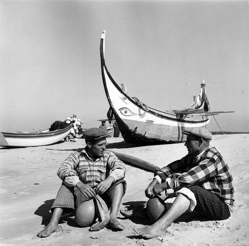 Portuguese fishermen relax near their traditional fishing boats on a beach near Lisbon.
