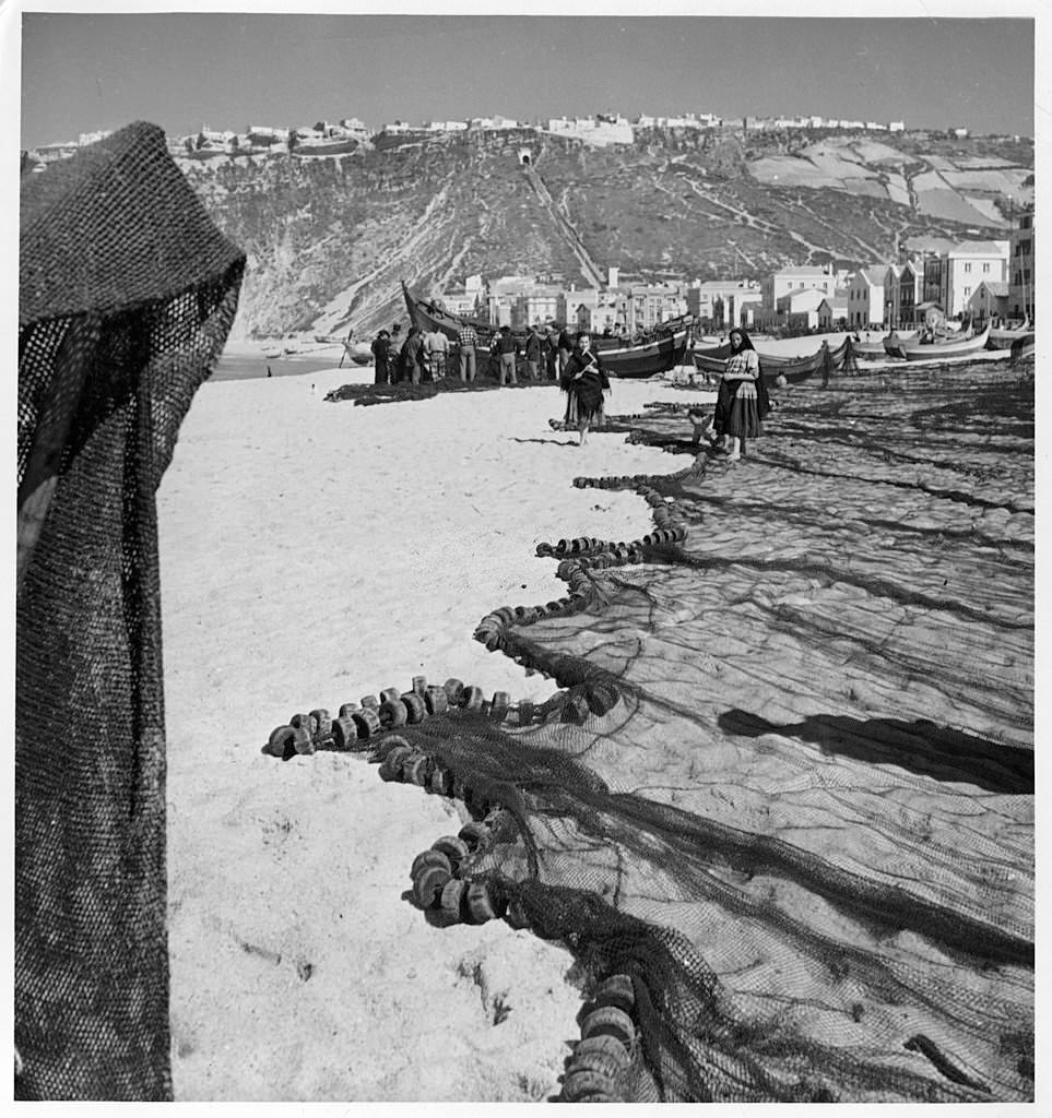 A view as fishermen layout their nets on the beach in Nazare, Portugal.