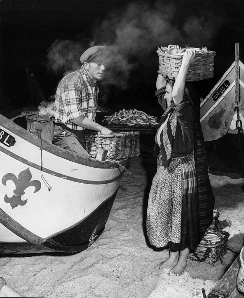 A fisherman and woman sell fresh fish from their boat in Nazare, a Portuguese fishing village.