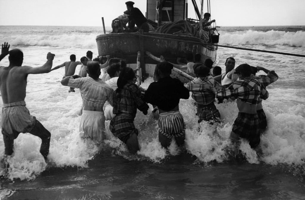 Launching of a fishing boat on a beach near Nazaré, Portugal, 1956