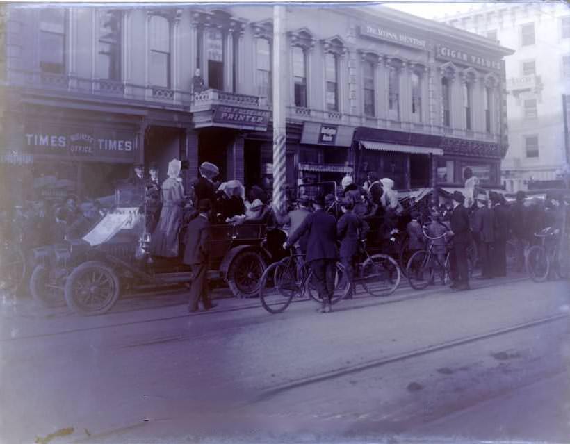 Scene with bikes, cars, people, buildings, 1910s