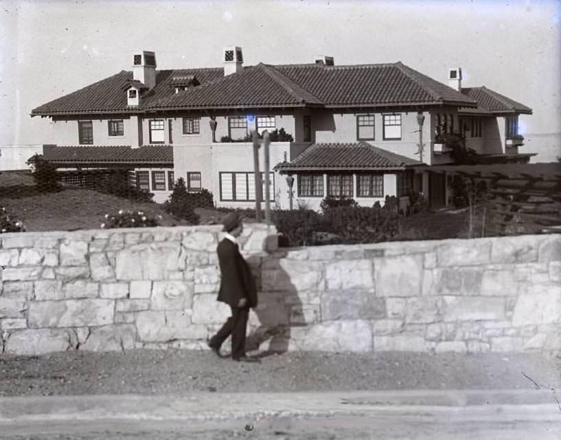 Man walking in front of grand house, 1900s