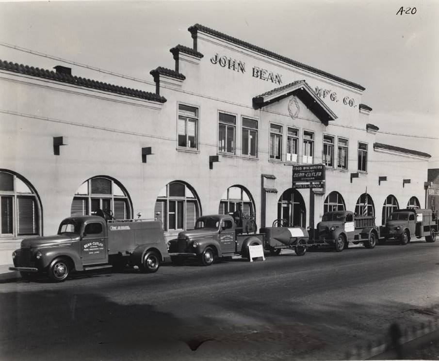 John Bean Manufacturing Co. building. Fleet of trucks parked along street, 1940s