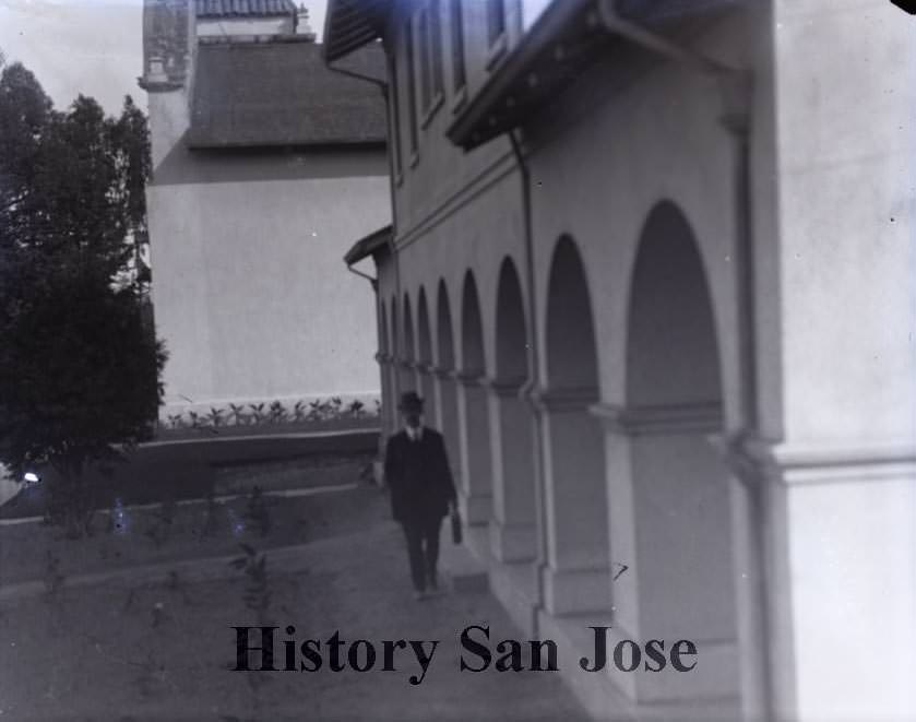 Man walking in front of building, 1890s