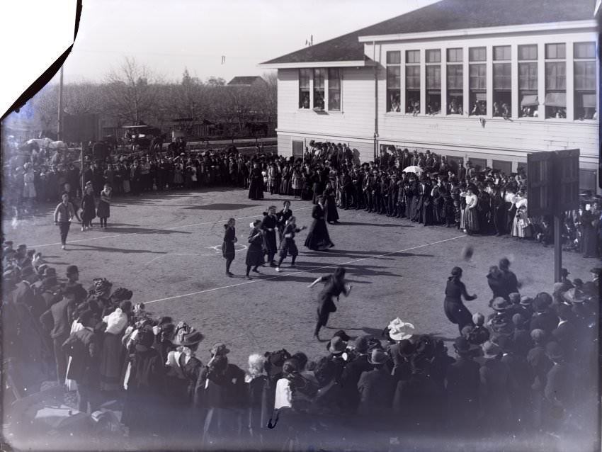 School yard, girls basketball players identified as CUHS, 1880s