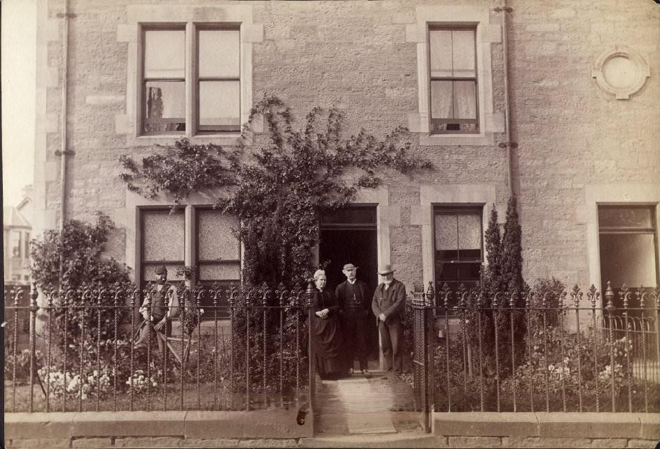Portrait of two young children outside stone house, 1900s