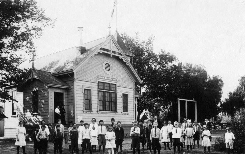 About thirty children of various ages stand in front of Doyle School, 1910