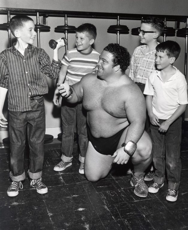 Wrestler weight training with local fans, 1953