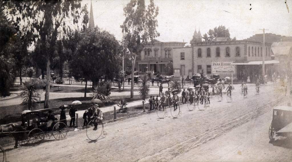Bicyclists riding past St. James Park, 1900