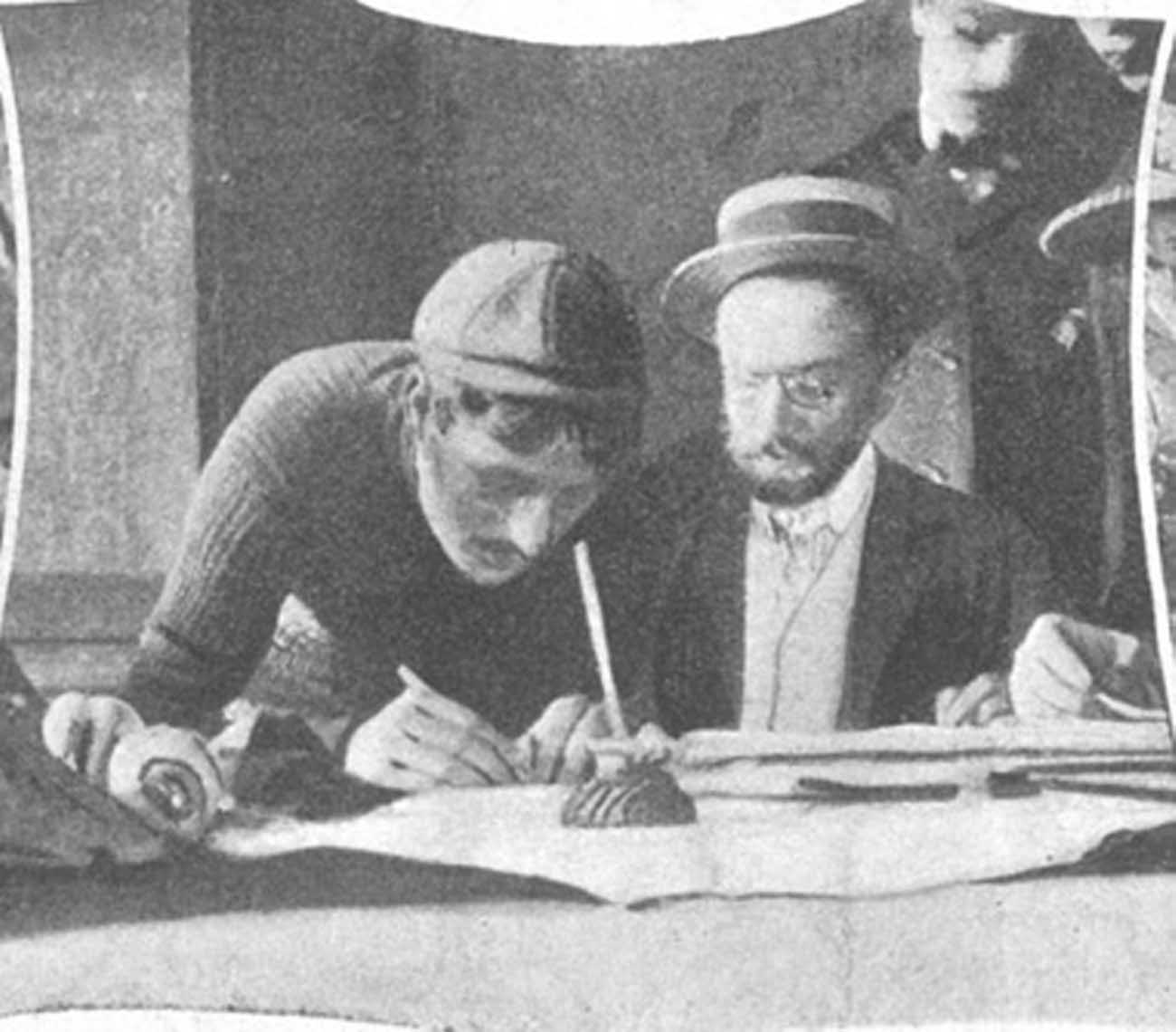 Leon Georget signs in under the watchful eye of an official.