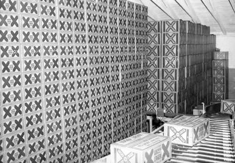 Boxes of Lucky Lager beer sit next to a production line at the Lucky Lager Brewery in Vancouver, 1953