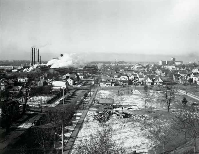 A view of 6th Street along Esther Short Park, 1930s. The railroad bridge is visible in the distance.