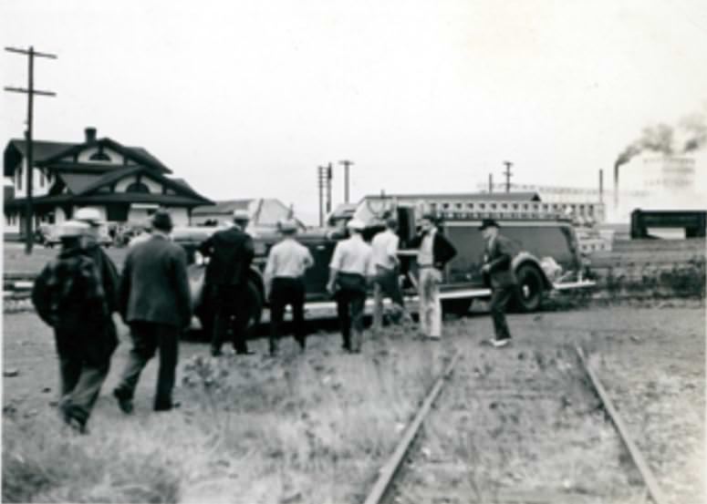 Men stand around a fire truck with a ladder parked near the train station in Vancouver, 1940