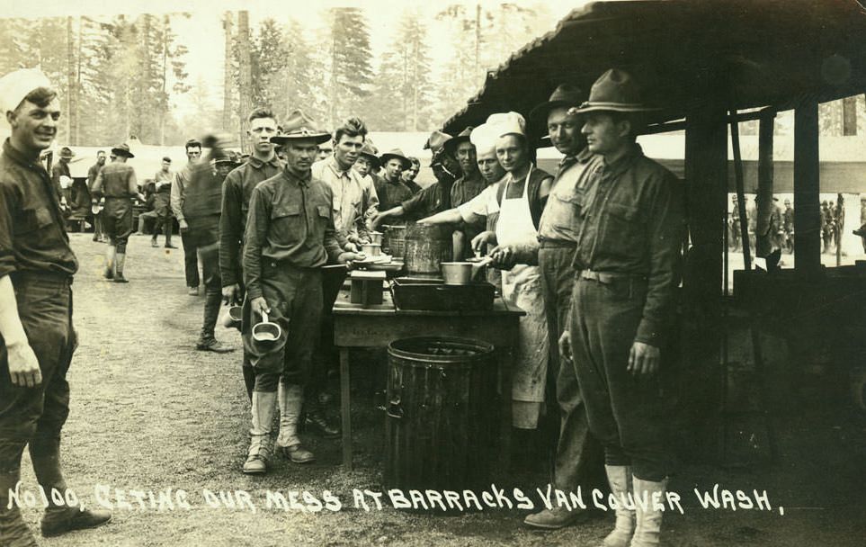 Soldiers stand in line or hover in the background to receive their meal, 1918